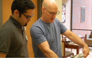 Preston Vienneau (left) working with Lain York (right) to hang art exhibit