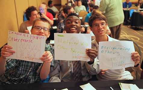 Three boys holding up signs with job interests
