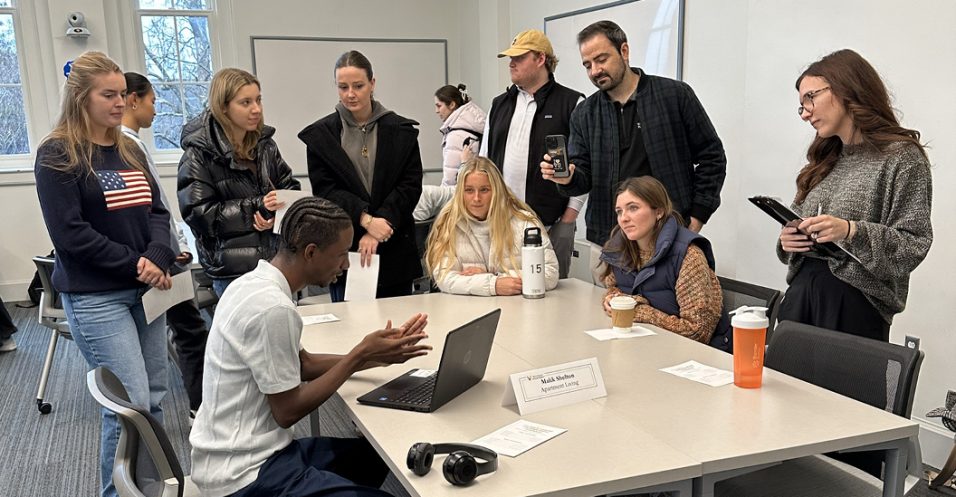 Students sit around a table enjoy a presentation