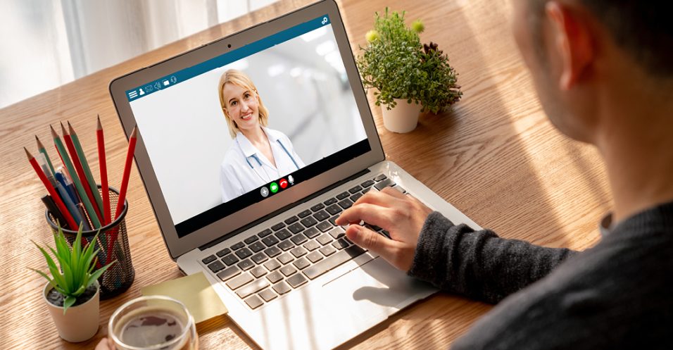 A man video chatting with a doctor on his laptop, engaged in a virtual consultation