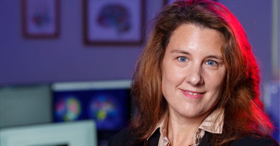 Close-up portrait of Dr Cutting with computer monitors in the background.