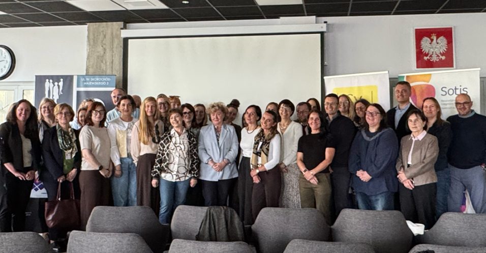 TRIAD staff members with colleagues from Poland posing for a large group photo in a conference room.